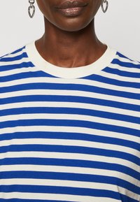 Blåt og hvidt stribet T-shirt med rund halsudskæring og ribbet krave. Materialet virker blødt og strækbart, velegnet til afslappet brug.
