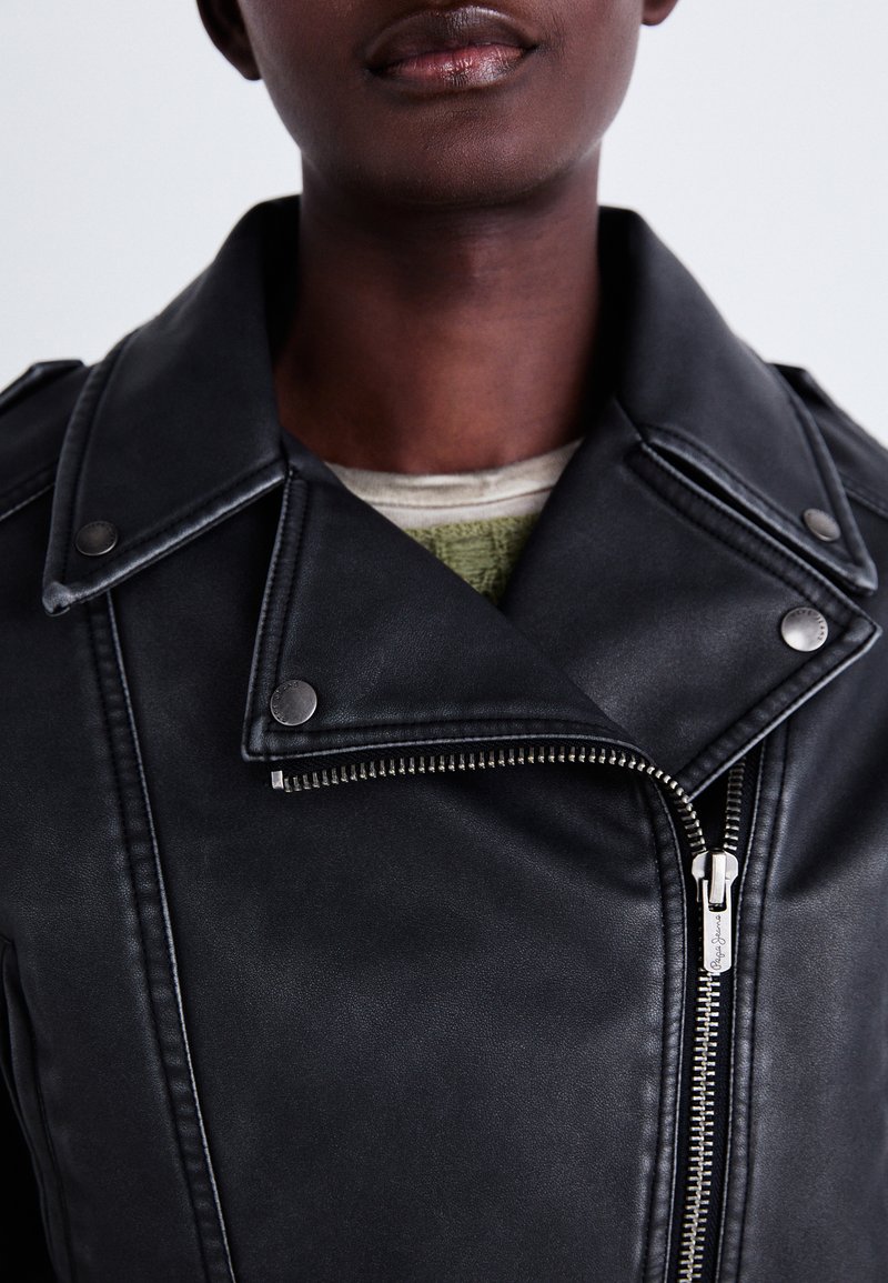 Veste de moto en cuir noir avec des zippers argentés et des boutons-pression. Caractéristiques : col cranté et texture lisse.