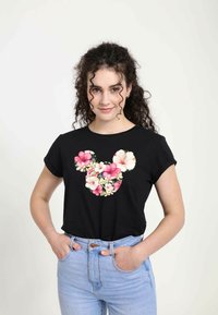 Sort kortærmet t-shirt med et blomsterdesign af Mickey Mouse i pink og hvide blomster, parret med lyseblå jeans.