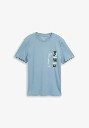 Lichtblauw T-shirt met korte mouwen en ronde hals, met verticale witte tekst en drie kleine zwart-wit architectuurfoto's op de borst.
