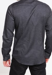 Grå langærmet skjorte med tekstureret finish, med en buet kant, knapmanchetter og en enkel rygdetalje.