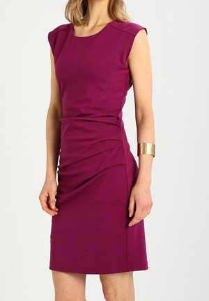 Dopasowana sukienka w głębokim odcieniu magenty, z krótkimi rękawkami, marszczeniem po bokach i gładką fakturą. Uzupełniona złotą bransoletką.