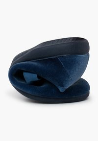 Zapato tipo slip-on de terciopelo azul con forma redondeada, parte superior texturizada y suela exterior de goma flexible. Presenta una correa de tela enrollada para un fácil uso.