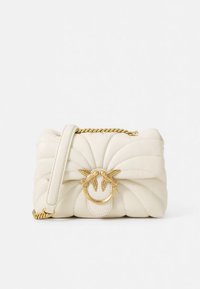 Mala creme acolchoada com design estruturado, apresentando um fecho dourado com tema de pássaro e alça de corrente. Textura suave com detalhes subtis de costura.