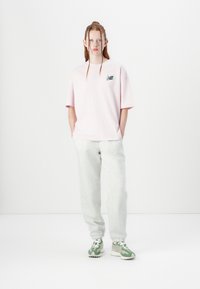 Light pink oversized t-shirt with logo, grey sweatpants, and green athletic shoes with white accents and textured sole. Simple, sporty outfit.