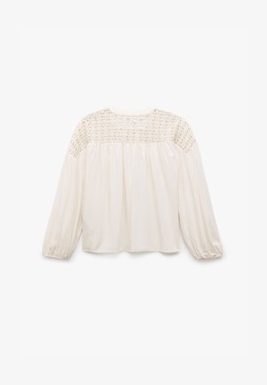 Blusa crema con maniche lunghe a sbuffo. Presenta un design in pizzo all'yoke e un corpo plissettato per una vestibilità ampia. Tessuto morbido al tatto.