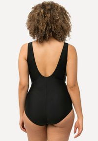 Maillot de bain une pièce noir avec un dos en V profond, des bretelles larges et une texture lisse. Il présente un design ajusté qui épouse le corps.
