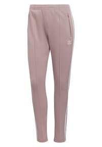 Rosa polyester joggers med vita sidostråk, elastisk midja och en ficka med dragkedja. Har en liten vit logotyp på vänster lår.