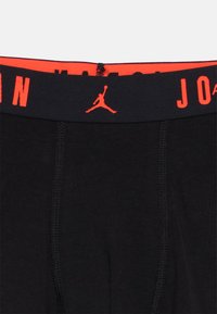 Μαύρα ανδρικά εσώρουχα boxer με κόκκινη ελαστική μέση που φέρει το κείμενο «JORDAN» και το λογότυπο Jumpman. Μαλακό ύφασμα και ομαλές λεπτομέρειες ραφής.