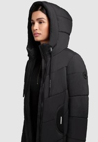 Giacca a vento nera con cappuccio, con texture trapuntata, zip frontale, coulisse e tasche laterali con dettagli in rete.
