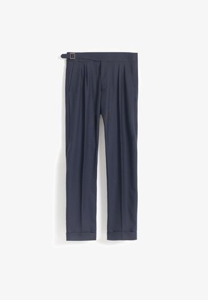 Pantalones ajustados azul marino con bolsillos laterales, pliegues, dobladillos con puños y un cinturón con hebilla sobre un fondo blanco liso.