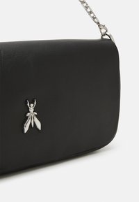 Black leather handbag with a sleek design, featuring a silver insect-shaped embellishment and a chain strap. Smooth texture, minimalist style.
