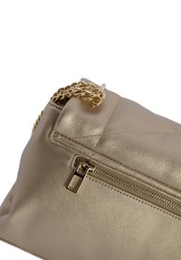 Bolso de mano metálico dorado con una textura de cuero suave, que cuenta con un cierre de cremallera y una correa de cadena dorada para llevar. Diseño simple y elegante.