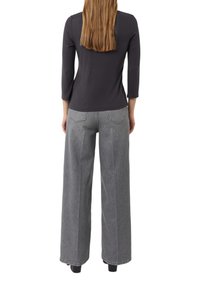 Dunkelgraues Jersey-Oberteil mit Dreiviertelärmel, kombiniert mit weit geschnittenen grauen Jeans. Beide Kleidungsstücke weisen minimale Nähedetails auf.
