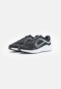 Chaussures de sport noires avec tige en mesh, accents gris contrastants et semelle blanche. Dispose d'un nez arrondi et d'un design à lacets.