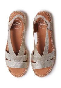Zlaté espadrilky na platformě s několika tkanými popruhy a otevřenou patou. Vyznačují se strukturovaným textilním svrškem a hladkou hnědou koženou stélkou.