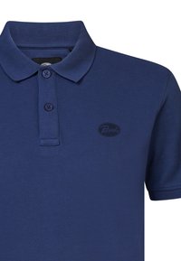 Mörkblå polo shirt gjord av strukturerad bomull. Har en krage, tre knappslutningar och en diskret logotyp på bröstet.