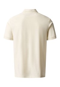 Polo beige clair uni à manches courtes, vu de dos, avec col classique et couture simple au bas.