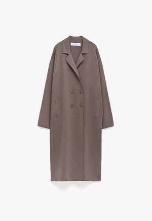 Manteau en laine taupe double boutonnage, long, avec larges revers et deux poches latérales, présenté sur fond blanc.