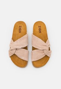 Ljusrosa mocka sandaler med tvistade remmar, brun texturerad innersula och logotyp inuti. Slip-on-design med öppen tå och platt sula.