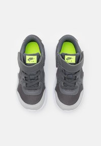 Grå Nike-sneakers med ovandel av mesh och syntetiskt läder, vit sula, kardborreband och neongrön innersula. Skorna har rund tå och snören.