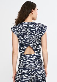 Granatowy top z białym nadrukiem zebry, krótkie rękawy, wycięcie w kształcie klucza z tyłu i zamek błyskawiczny na środku. Gładki, lekki materiał.