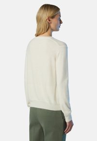 Cremefarbener Strickpullover mit rundem Ausschnitt, langen Ärmeln und gerippten Bündchen. Weiches, strukturiertes Material mit lockerer Passform.