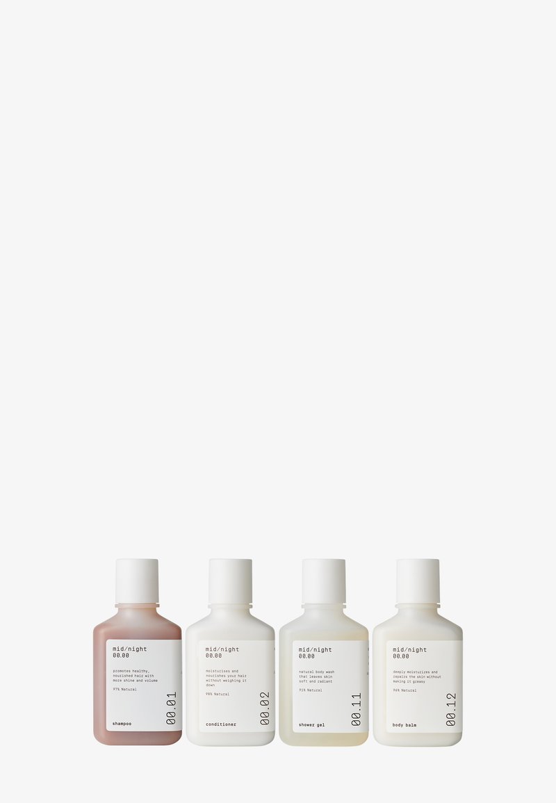Quatre bouteilles de produits de soin capillaire et corporel : shampoing (rose), après-shampoing (blanc), gel douche (blanc), baume corporel (blanc). Design minimaliste avec étiquettes.