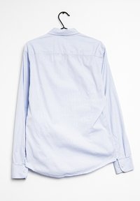 Camicia a maniche lunghe azzurro chiaro appesa a un gancio. Presenta un colletto a punta, polsini con bottoni e un sottile motivo a quadretti sul tessuto.