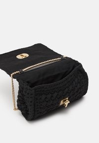 Borsa a tracolla nera intrecciata con una superficie testurizzata, tracolla in catena dorata e un fermo sicuro in oro, dotata di un ampio e morbido interno.