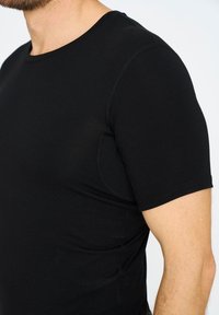 Sort t-shirt med korte ærmer lavet af blødt stof, med en rund halsudskæring og diskret syning langs kanterne.
