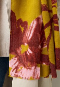 Mitmevärviline sall, millel on kollase, roosa ja punase lillemustrid. Pehme tekstuur, narmendavate servadega ja ristküliku kujuga.