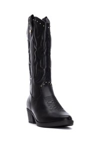 Bota vaquera de cuero negro con caña cónica, costuras decorativas, tachuelas doradas y tacón apilado. Presenta puntera puntiaguda y detalles texturizados.