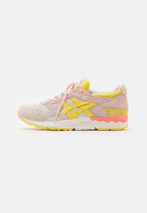 Lyserød og gul sneaker med perforerede detaljer, snørebånd og en hvid sål med koral- og gule accenter, set fra siden.
