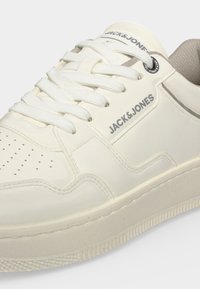 Baskets blanches Jack & Jones avec lacets blancs, zone des orteils perforée et logo de la marque sur le côté et la languette.