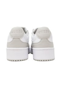 Weiße Plateau-Sneaker mit hellgrauen Fersenakzenten und dem auf der Rückseite geprägten Schriftzug "GUESS", von hinten auf einem weißen Hintergrund gezeigt.