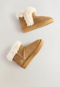 Beige Wildleder-Stiefeletten mit weißem Kunstfellbesatz oben, runder Zehenform und Gummisohle, mit genähten Details und strukturierter Oberfläche.