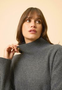 Grau geripptes Rollkragensweater aus weichem Material, mit hohem Kragen und langen Ärmeln, eng am Hals anliegend und mit strukturierter Oberfläche.