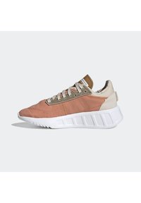 Athletic shoe with a pink and beige fabric upper, textured design, beige accents, and molded white rubber sole. Features grey laces.