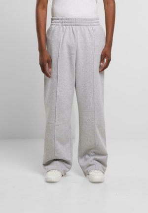 Light gray, wide-leg sweatpants with an elastic waistband, featuring stitched seams and worn with white sneakers. Soft, textured fabric.