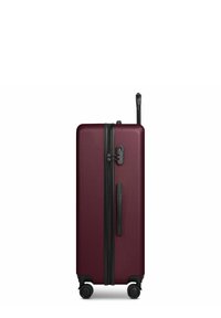 Grande valise rigide couleur bordeaux avec quatre roulettes noires pivotantes, poignée latérale, fermeture éclair et poignée télescopique déployée.