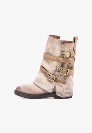 Beżowe zamszowe botki sięgające kostki z trzema brązowymi skórzanymi paskami, mosiężnymi klamrami i lekko uniesionym obcasem. Okrągły czubek i teksturowane wykończenie.