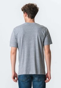 Grå bomulds t-shirt med korte ærmer, rund halsudskæring og en afslappet pasform. Glat tekstur uden synlige mønstre. Bæres med blå denim jeans.