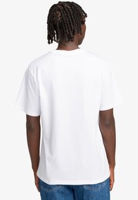 White cotton t-shirt with a relaxed fit, short sleeves, and a round neckline. Smooth texture, minimalistic design with no visible graphics.