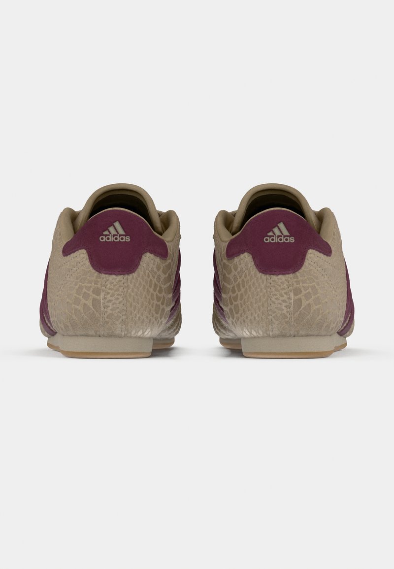 Chaussures Adidas avec un schéma de couleurs beige et violet, présentant un motif texturé, un matériau en daim lisse et un design profilé bas.