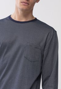 Maglietta a maniche lunghe blu navy con scollo rotondo, dotata di una piccola tasca sul petto e fini righe orizzontali in un tessuto testurizzato.