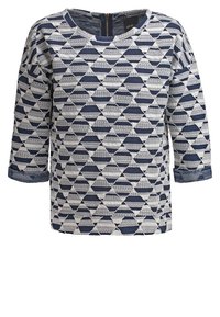 Pull avec motif géométrique de triangles bleu marine et blanc, manches trois-quarts, encolure ronde et fermeture éclair au dos.