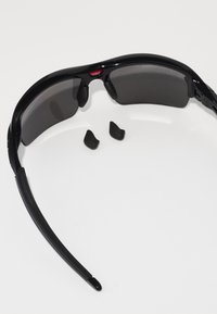Gafas de sol negras con lentes oscuros, que presentan un diseño elegante y curvado. Incluyen dos pequeñas almohadillas nasales negras. Material resistente con acabado mate.