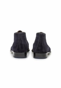 Botas de ante hasta el tobillo en azul marino oscuro con una textura suave, punta redondeada y un tacón bajo negro. Las costuras decorativas realzan el diseño.