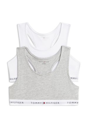 Zwei Tommy Hilfiger Racerback-Sport-BHs, einer hellgrau und einer weiß, gestapelt mit elastischen Bändern unten.